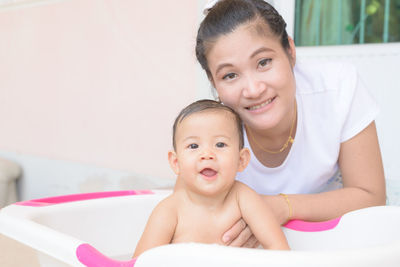 Portrait of mother with daughter in bathtub at home