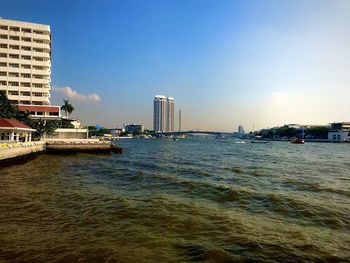 Sea by buildings against clear sky