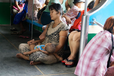 Women sitting on the wall with people in background