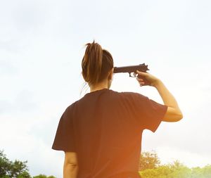 Rear view of woman holding gun to her head