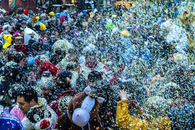 Crowd throwing colorful confetti in city during celebration