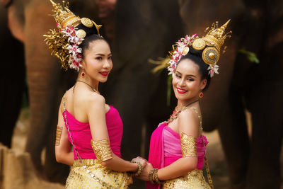 Females in traditional clothing sitting by elephants