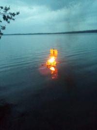 Fire floating on sea against sky during sunset