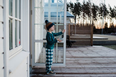 Boy standing at his back door holding a cereal bowl looking outside