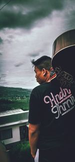 Young man standing by sea against sky