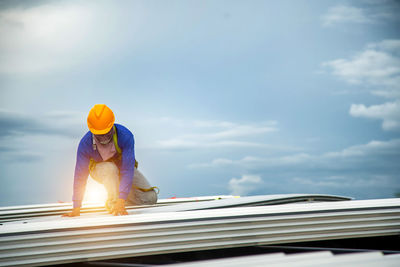 Asian construction workers are installing metal roofing sheets for industrial roof installations.