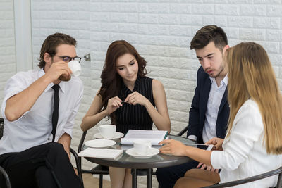 Business colleagues discussing while sitting at table in office