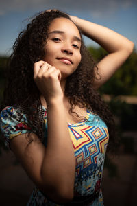 Portrait of teenage girl standing with hand in hair