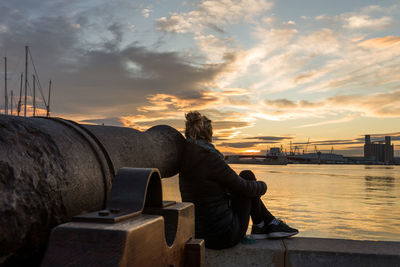 Rear view of woman sitting against orange sky