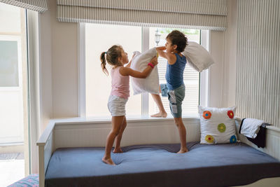 Brother and sister playing at home pillow fight