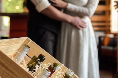 Midsection of woman standing by glass bottles