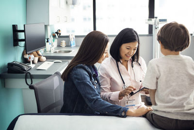 Female doctor using tablet computer with family in clinic