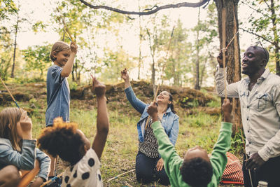 Multi-ethnic family holding skewers at picnic spot in park