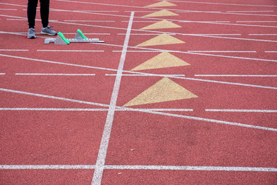 One runner stands by a starting block on an empty athletic track