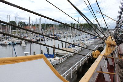 Sailboats moored on bridge against sky