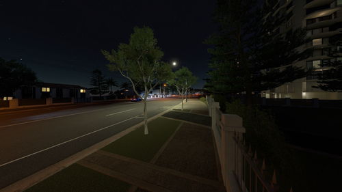 Road by illuminated city at night