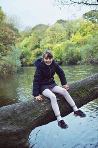 Portrait of boy on lake against trees