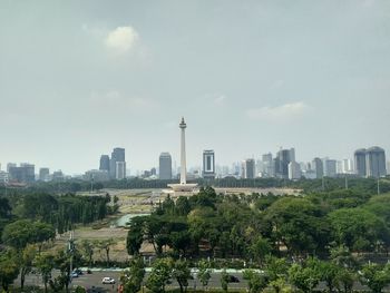 Trees and buildings in city against sky