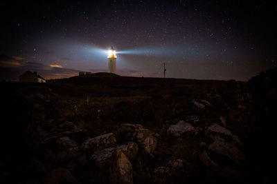 Scenic view of lighthouse on hill against sky at night