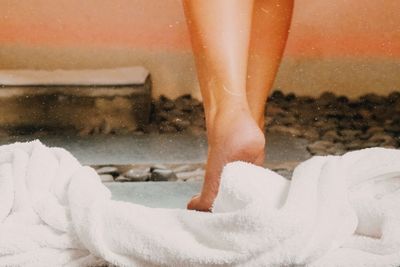 Low section of woman standing on wet shore