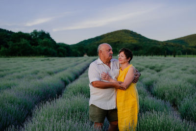 Rear view of couple standing on field against sky