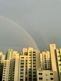 Low angle view of rainbow over buildings against sky