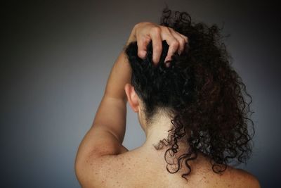 Rear view of shirtless woman against gray background