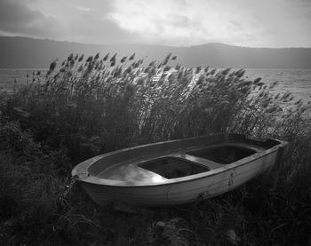 Abandoned boat on field against sky