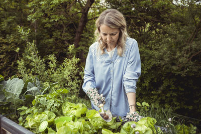 Mid adult woman standing against plants