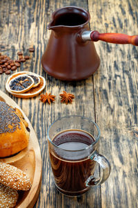 Freshly made espresso coffee in clear glass cup stands next to muffin on old striped wooden table. 