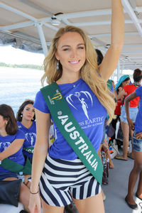 Portrait of smiling young woman standing against people