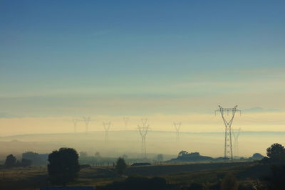 Electricity pylons on land against sky