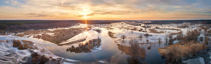 Panoramic view of snow covered landscape against sky during sunset