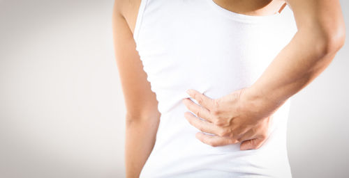 Midsection of woman standing against white background