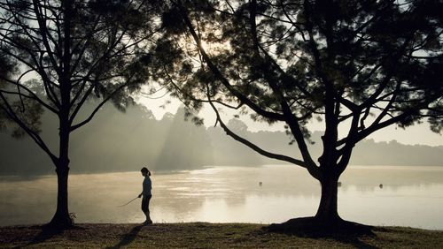 Man standing by tree on lake