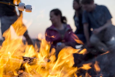 Close-up of campfire against fiends camping at dusk