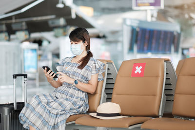 Midsection of woman using mobile phone while sitting on seat