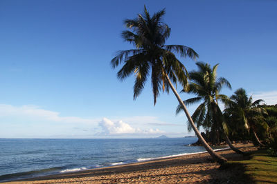 The view on a beach with sea, blue sky and white sand on a sunny day.