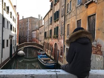 Rear view of woman walking on canal in city during winter