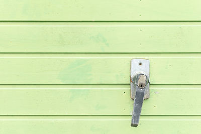 Metal door handle with keyhole on a green garage door.