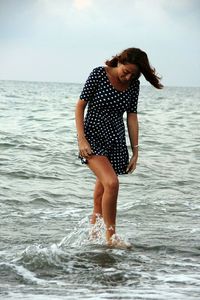 Full length of young woman standing at beach