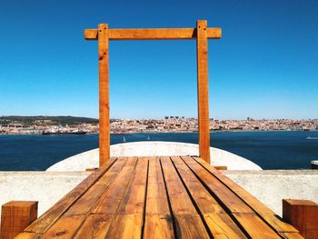 Pier on sea against clear blue sky