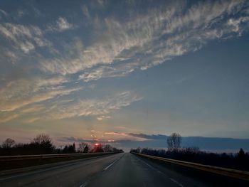 Country road against sky at sunset