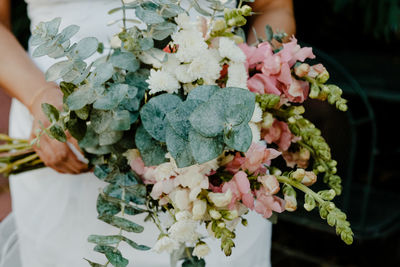 Midsection of bride holding bouquet