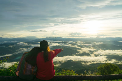 Woman standing on mountain against sky during sunset