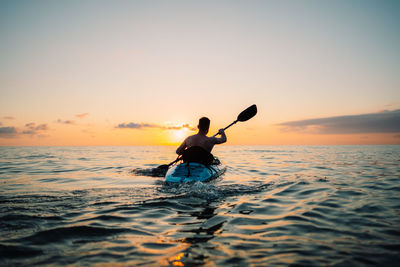 A man is sailing on a sup board at sunset on the sea. high quality photo