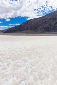 Scenic view of badwater by mountain at death valley national park against sky