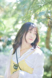 Young woman standing against trees