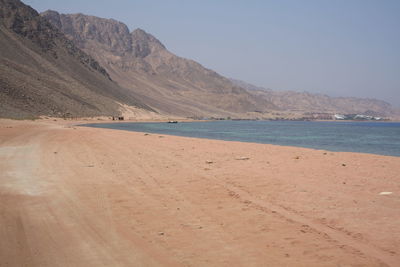 Scenic view of beach and mountains against clear sky
