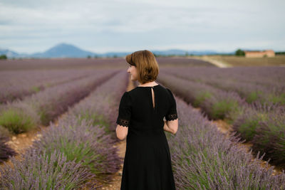 Rear view of woman standing between blossoms of lavender field 